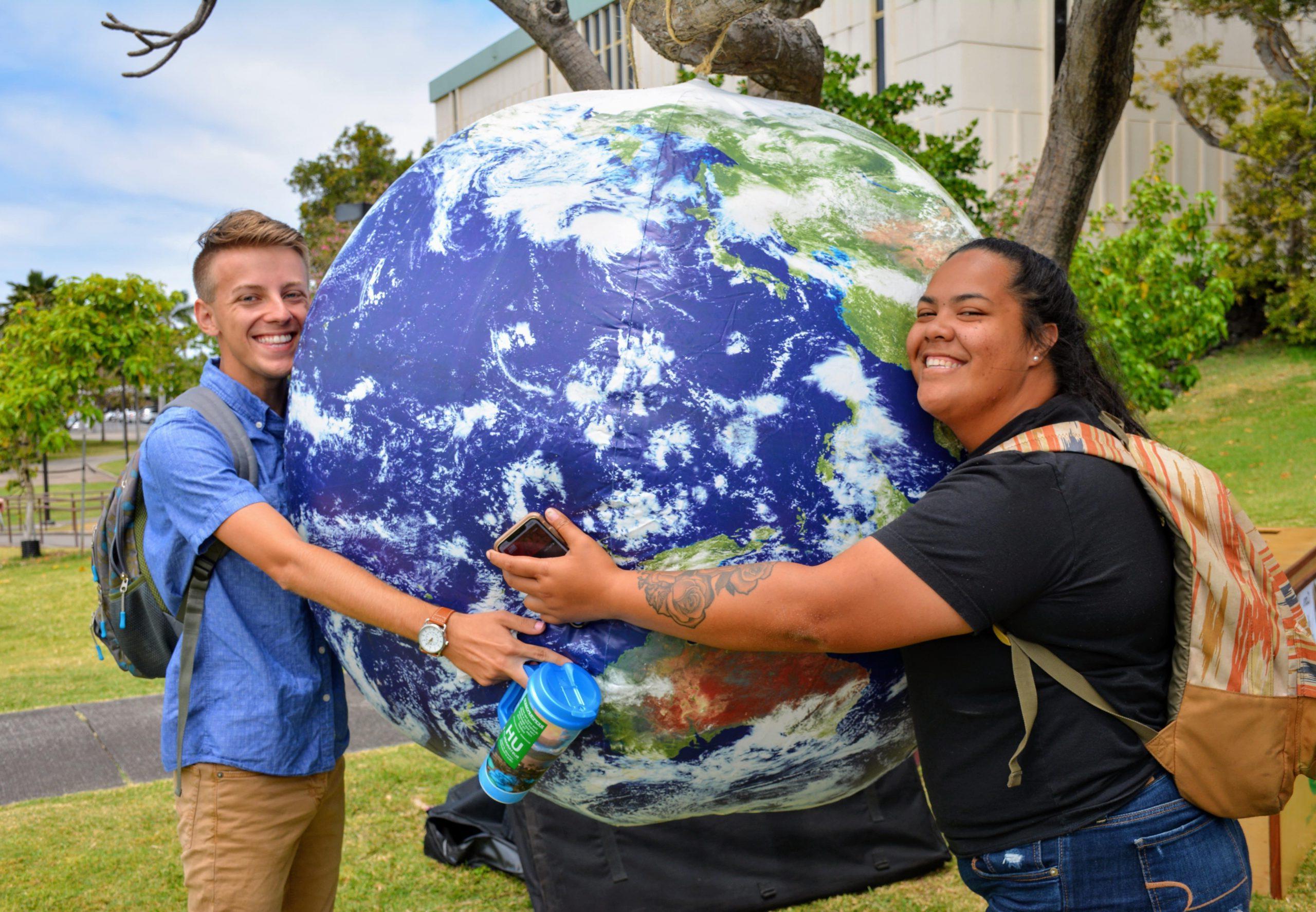 Two students hugging a inflatable globe